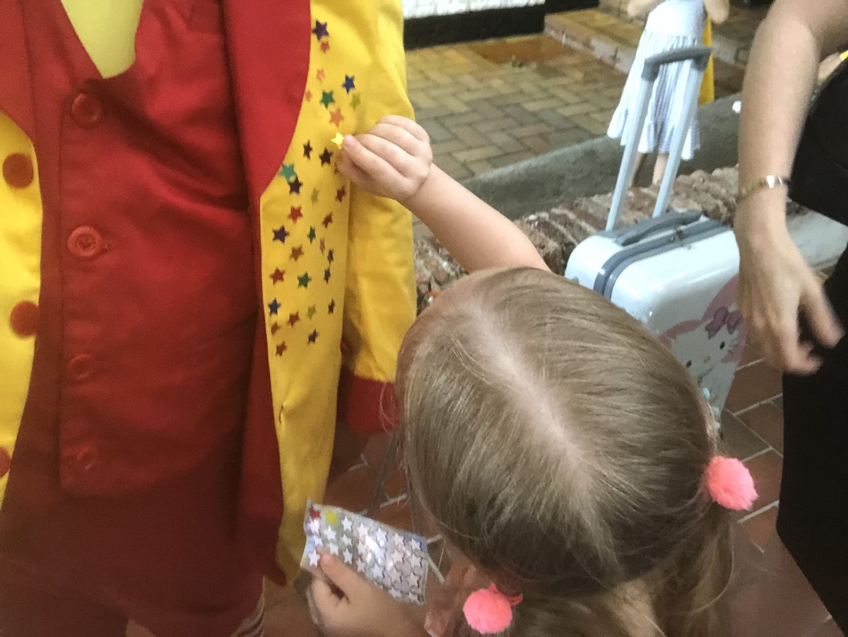 A young guest placing star stickers on Maddie's jacket